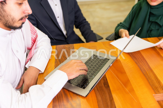 اجتماع اداري مع مجموعة من الأشخاص السعوديين الخليجيين في غرفة الاجتماعات  ، اجتماع رجال اعمال و سيده اعمال سويا داخل الشركة ، استخدام الكمبيوتر المحمول لادارة الاعمال ،  شركة سعودية ، عمل خليجي ،  فريق العمل 