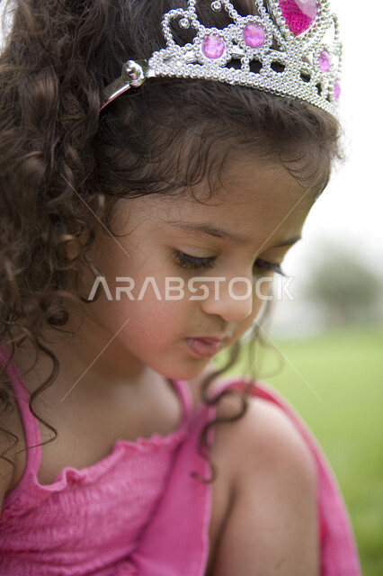 تعزيز الثقة بالنفس وتقوية الشخصية للاطفال, تقمص وتقليد شخصيات الاميرات الكرتونية, الاهتمام بالانوثة و الاناقة منذ الصغر, صورة مقربة لفتاة صغيرة عربية خليجية إماراتية ترتدي فستان وتاج الأميرة  في إحدى الحدائق العامة