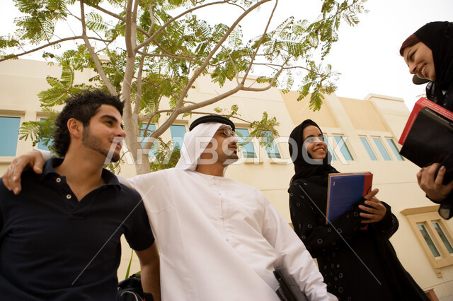 طلاب جامعيون عرب خليجيون إماراتيون من الذكور والإنات يقفون في الحرم الجامعي، إيماءات السرور والسعادة بالتعارف على الزملاء وبناء الصداقات الجديدة، حوارات ونقاشات طلابية في الجامعة، تبادل الحديث أثناء وقت الإستراحة، الجامعات والكليات الإماراتية