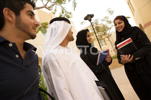 إيماءات السرور والسعادة بالتعارف على الزملاء وبناء الصداقات الجديدة، زملاء جامعيون عرب خليجيون إماراتيون من الذكور والإنات في الحرم الجامعي ويستمتعون بتبادل الحديث أثناء وقت الإستراحة، حوارات ونقاشات طلابية في الجامعة، الجامعات والكليات الإماراتية