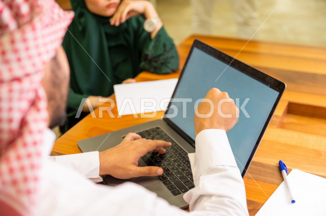 Administrative meeting with a group of Saudi Gulf people in the conference room, meeting of businessmen and a businesswoman together inside the company, using a laptop computer to manage a business, a Saudi company, Gulf work, work team