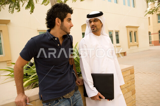 حوارات ونقاشات طلابية في الجامعة، طالبان جامعيان عربيان خليجيان إماراتيان يستمتعان بتبادل الحديث أثناء وقت الإستراحة في الحرم الجامعي، التعارف على الزملاء وبناء الصداقات الجديدة، تبادل المعلومات والمعرفة بين الطلاب، الجامعات والكليات الإماراتية