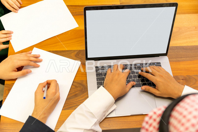 اجتماع اداري مع مجموعة من الأشخاص السعوديين الخليجيين في غرفة الاجتماعات  ، اجتماع رجال اعمال و سيده اعمال سويا داخل الشركة ، استخدام الكمبيوتر المحمول لادارة الاعمال ،  شركة سعودية ، عمل خليجي ،  فريق العمل 