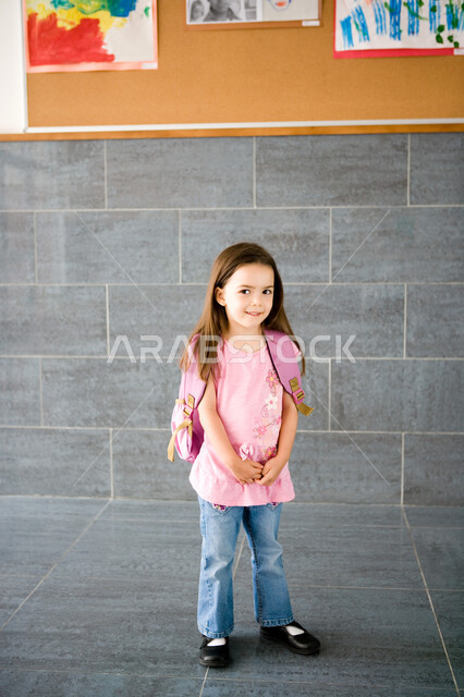 بداية عام دراسي جديد, تلميذة عربية خليجية إماراتية ترتدي حقيبة الظهر المدرسية, الاستمتاع بالتقاط الصور بإيماءات السعادة والسرور, المدارس الأكاديمية في الإمارات العربية المتحدة, صورة الجسم بالطول الكامل