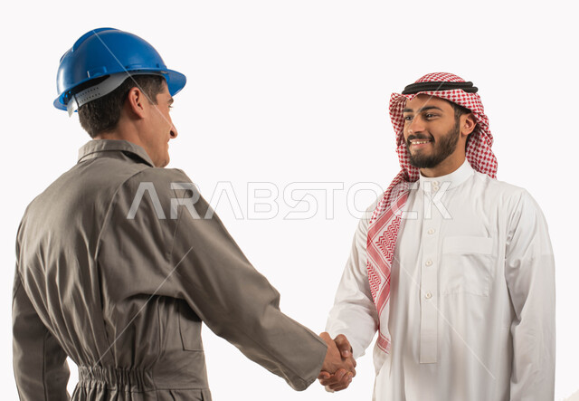 الاتفاق على انجاز مهام العمل, بورتريه مقرب لرجل عربي خليجي سعودي مبتسم يرتدي الثوب التقليدي والشماغ يصافح مهندس كهرباء, عامل صيانة يرتدي خوذة الحماية الواقية, التعارف وبناء العلاقات الاجتماعية, مهن ووظائف سعودية, العمل في القطاع الهندسي, خلفية بيضاء
