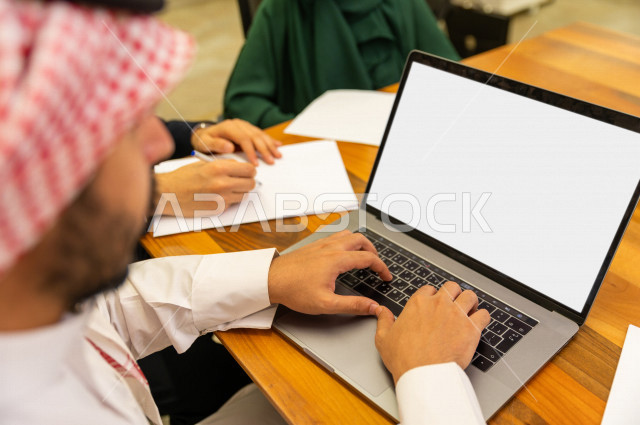 Administrative meeting with a group of Saudi Gulf people in the conference room, meeting of businessmen and a businesswoman together inside the company, using a laptop computer to manage a business, a Saudi company, Gulf work, work team