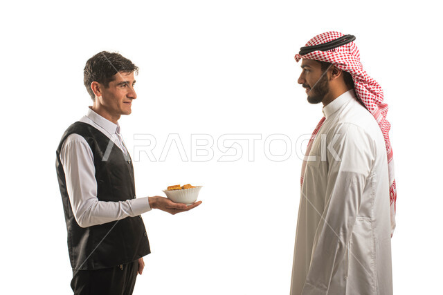 أصناف من المأكولات الشهيه العربية اللذيذه, بورتريه مقرب لنادل عربي خليجي سعودي يرتدي الزي الخاص بالعمل يقوم بتقديم طبق من الطعام لرجل سعودي يرتدي الزي التقليدي , الاهتمام والعناية بالزبائن, مطابخ ومطاعم شرقيه سعودية, خلفية بيضاء