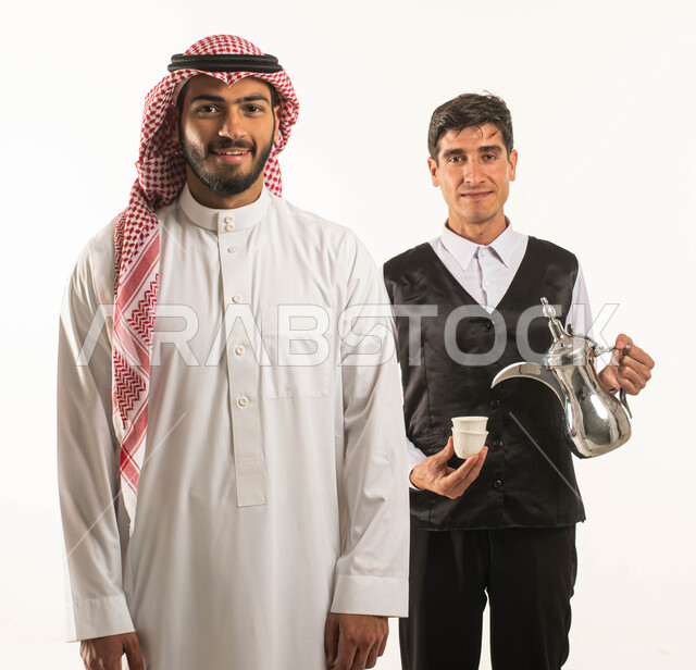 تقديم المشروبات الساخنة في المقاهي والكافيهات ،حسن الضيافه والاستقبال، بورتريه لرجل عربي سعودي خليجي يرتدي الثوب والزي التقليدي يقف بجانب نادل سعودي يرتدي اللباس الخاص بالعمل وينظران إلى الكاميرا ،خلفية بيضاء