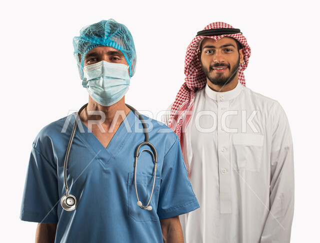 أداء الواجبات الطبيه بجودة عالية ، بورتريه مقرب لطبيب عربي سعودي خليجي يرتدي اللباس الخاص بالطب يقف بجانب مريض سعودي يرتدي الثوب والزي التقليدي وينظران إلى الكاميرا، إجراء الفحوصات الطبية الدورية، التشخيص السريع و الفحص الطبي، خلفية بيضاء