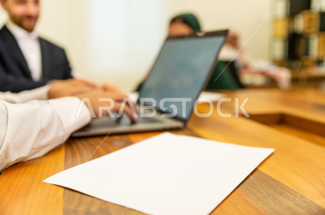 اجتماع اداري مع مجموعة من الأشخاص السعوديين الخليجيين في غرفة الاجتماعات  ، اجتماع رجال اعمال و سيده اعمال سويا داخل الشركة ، استخدام الكمبيوتر المحمول لادارة الاعمال ،  شركة سعودية ، عمل خليجي ،  فريق العمل 