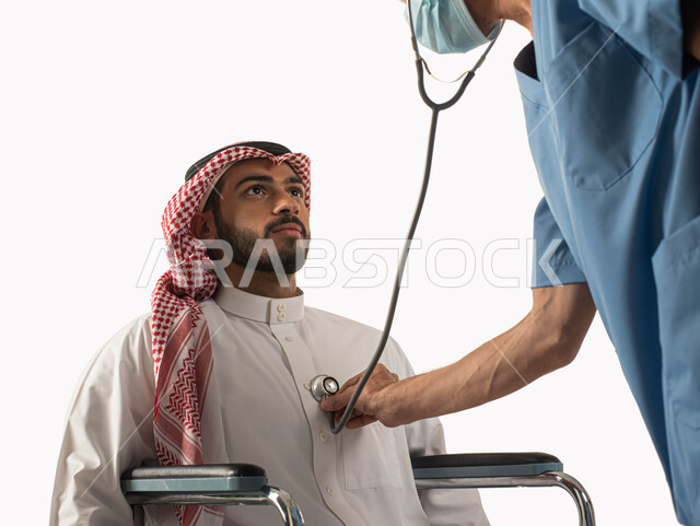 تأمين معدات و أجهزه تساعد على الحركه, تحسين حياة أصحاب الهمم و الحفاظ على صحتهم بالفحوصات الطبيه الدورية, سماع نبضات القلب من خلال السماعه، مريض مقعد يجلس على كرسي متحرك في زيارة للطبيب, بورتريه مقرب لرجل عربي سعودي خليجي يرتدي الزي التقليدي، خلفية بيضاء