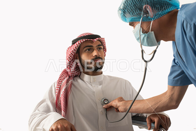 تحسين حياة أصحاب الهمم والحفاظ على صحتهم بالفحوصات الطبيه الدورية, سماع نبضات القلب من خلال السماعه، مريض مقعد يجلس على كرسي متحرك في زيارة للطبيب, تأمين أجهزة ومعدات تساعد على الحركه, بورتريه مقرب لرجل عربي سعودي خليجي يرتدي الزي التقليدي، خلفية بيضاء