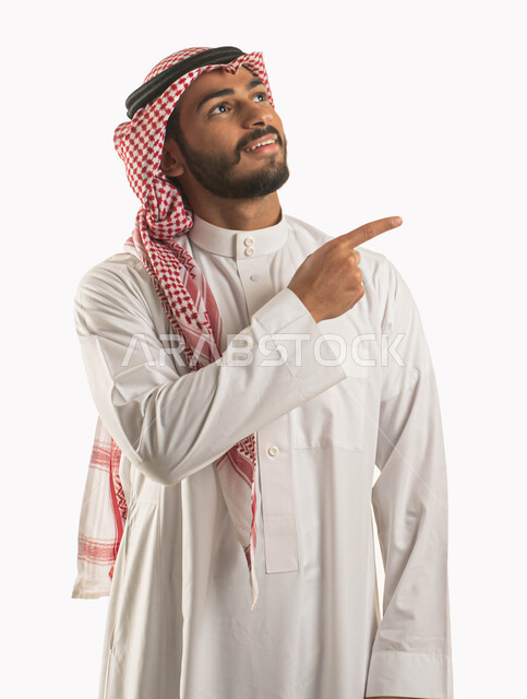 استخدام حاسة اللمس لتحريك العناصر الهولوجراميه, بورتريه مقرب لشاب عربي خليجي سعودي  يرتدي الثوب والزي التقليدي بإيماءات يدين تشير الى شيء ما, النقر على الشاشه, الشعور بالإعجاب والرضى, البهجه والسرور، خلفية بيضاء