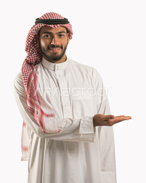 ايماءات تدل على السرور و السعادة, تقنية الهولوجرام ثلاثية الابعاد، إمساك وإحتواء عنصر هولوجرام ،بورتريه مقرب لرجل عربي سعودي خليجي يرتدي الثوب والزي التقليدي يرفع يده لعرض عنصر هولوجرامي والنظر إلى الكاميرا, خلفية بيضاء