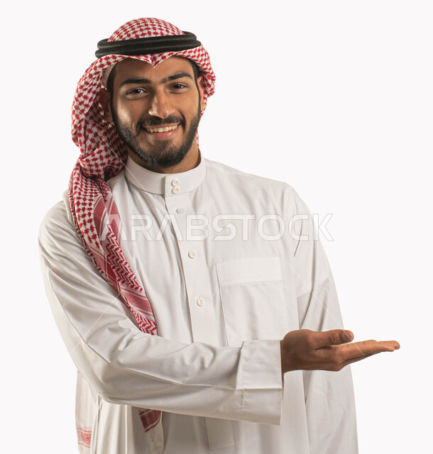 تقنية الهولوجرام ثلاثية الابعاد، إمساك وإحتواء عنصر هولوجرام ،بورتريه مقرب لرجل عربي سعودي خليجي يرتدي الثوب والزي التقليدي يرفع يده لعرض عنصر هولوجرامي والنظر إلى الكاميرا, ايماءات تدل على السرور و السعادة, خلفية بيضاء