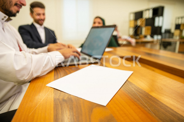 اجتماع اداري مع مجموعة من الأشخاص السعوديين الخليجيين في غرفة الاجتماعات  ، اجتماع رجال اعمال و سيده اعمال سويا داخل الشركة ، استخدام الكمبيوتر المحمول لادارة الاعمال ،  شركة سعودية ، عمل خليجي ،  فريق العمل 
