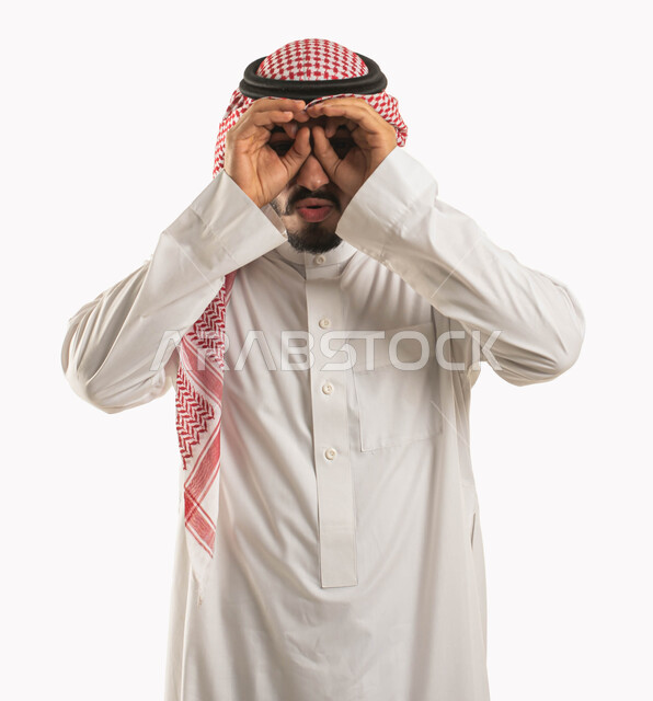 الأهداف والطموحات والرؤية المستقبلية، بورتريه لرجل عربي خليجي سعودي يرتدي الشماغ والثوب التقليدي ويضع يده على عينيه كالناظور، الاستكشاف والمغامرة مع فريق الكشافة، البحث والتخطيط والنظر للمستقبل، ايماءات الدهشة والذهول، خلفية بيضاء