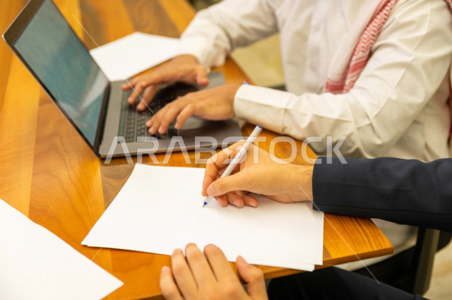 اجتماع اداري مع مجموعة من الأشخاص السعوديين الخليجيين في غرفة الاجتماعات  ، اجتماع رجال اعمال و سيده اعمال سويا داخل الشركة ، استخدام الكمبيوتر المحمول لادارة الاعمال ،  شركة سعودية ، عمل خليجي ،  فريق العمل 