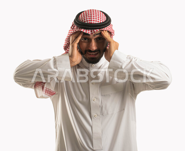 الاجهاد والضغط النفسي، بورتريه لرجل عربي سعودي خليجي يرتدي الشماغ والثوب التقليدي ويضع يده على رأسه، إيماءات وجه ويدين تدل على الصداع، الاحساس بألم شديد في الرأس، التوتر والارهاق وعدم الراحة، الشعور بالمرض والحاجة للعلاج، خلفية بيضاء