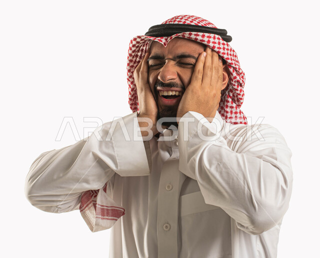 إيماءات وجه ويدين تدل على الصداع، بورتريه لرجل عربي سعودي خليجي يرتدي الشماغ والثوب التقليدي ويضع يده على رأسه، الاحساس بألم شديد في الرأس، التوتر والارهاق وعدم الراحة، الاجهاد والضغط النفسي، الشعور بالمرض والحاجة للعلاج، خلفية بيضاء