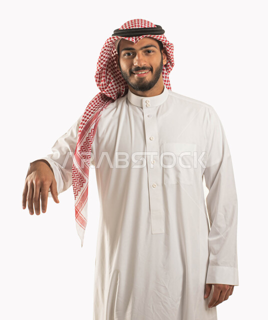 ايماءات الاستناد والارتكاز على شيء ما، بورتريه لشاب وسيم عربي خليجي سعوي يرتدي الشماغ والثوب التقليدي ويقف بإستقامة وينظر الى الكاميرا بسرور وسعادة، حركة يد واشارات لطلب القبلة لتنفيذ امر ما، خلفية بيضاء