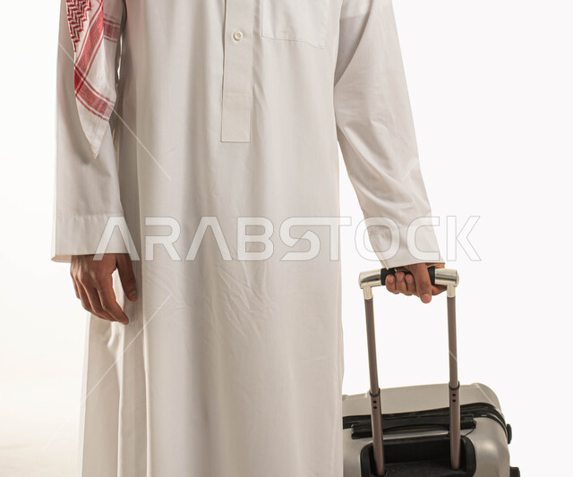 Spending a pleasant summer vacation, a close-up portrait of a Saudi Gulf Arab citizen holding a luggage bag, preparing to travel on a tourist tour, a trip for convalescence, entertainment, and relaxation, a white background.