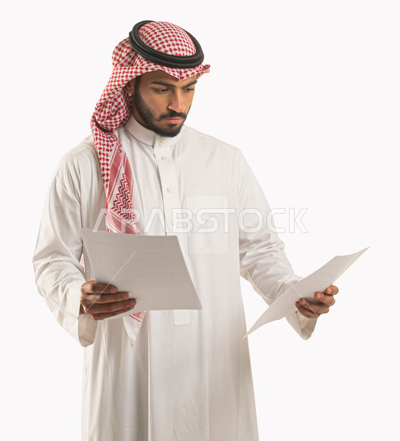 اعداد التقارير الخاصة بالعمل، بورتريه لرجل عربي خليجي سعودي يرتدي الثوب التقليدي والشماغ ويحمل بيده مجموعة من الاوراق البيضاء، مراجعة ومتابعة الخطط والمشاريع المكتبية، التدقيق في قراءة الملاحظات، خلفية بيضاء