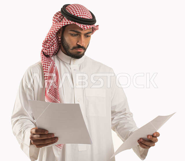 مراجعة ومتابعة الخطط والمشاريع المكتبية، بورتريه لرجل عربي خليجي سعودي يرتدي الثوب التقليدي والشماغ ويحمل بيده مجموعة من الاوراق البيضاء، اعداد التقارير الخاصة بالعمل، التدقيق في قراءة الملاحظات، خلفية بيضاء