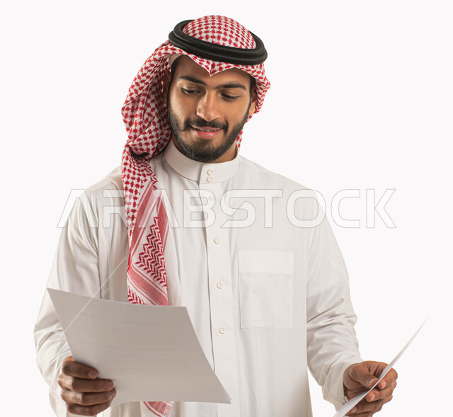 إعداد تقارير و مهام العمل, بورتريه لسكرتير عربي سعودي خليجي مبتسم يرتدي الثوب و الشماغ التقليدي يحمل بيده مجموعة من الأوراق البيضاء, التدقيق في قراءة الملاحظات و المعلومات, متابعة الخطط و المشاريع المكتبية, خلفية بيضاء .