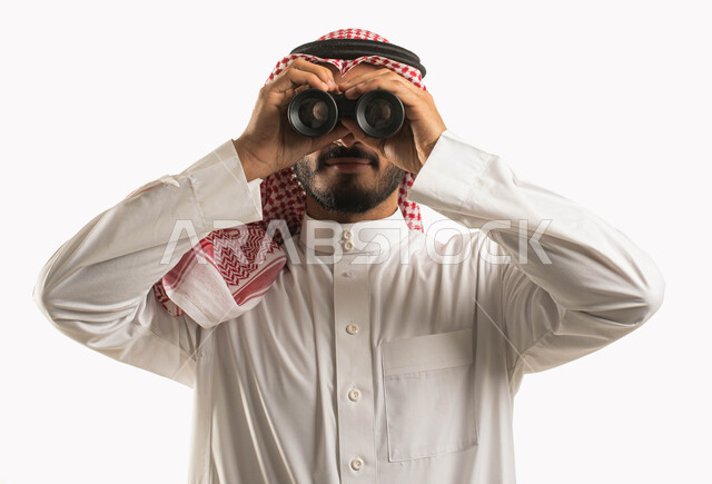 Seeing distant things through a telescope, love of exploration and adventure, close-up portrait of a Saudi Gulf Arab man wearing traditional clothing and a shemagh looking through a viewfinder, future planning for goals and ambitions, white background