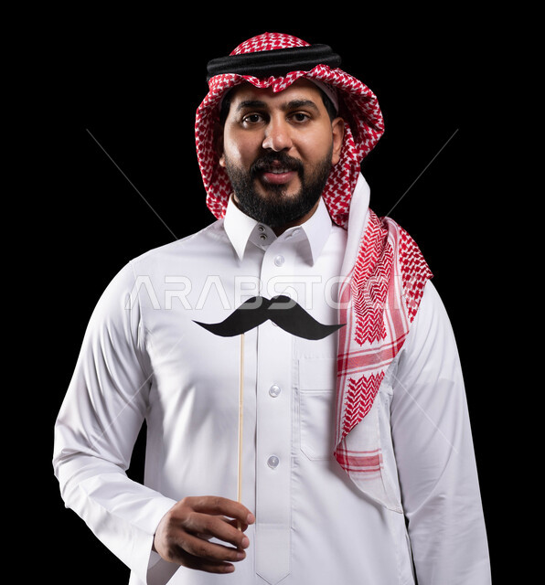 اليوم العالمي للرجل 19 نوفمبر، الاحتفال بالمناسبات العالمية، بورتريه لمواطن عربي خليجي سعودي يرتدي الثوب التقليدي والشماغ ويمسك عود خشبي مع قصاصة ورقية على شكل شارب، الاهتمام بصحة الرجل، خلفية سوداء