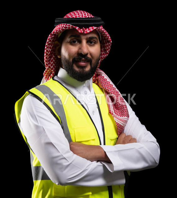 الرقابة على المشاريع الهندسية و تدقيق الاعمال ،مفهوم الهندسة والانشاءات المعمارية، بورتريه مقرب لمهندس عربي خليجي سعودي مبتسم  سترة الحماية ينظر إلى الكاميرا، الوقوف بإيماءات أيدي متقاطعه، مهن ووظائف سعودية، الإعمار بسواعد أبناء الوطن، خلفية سوداء