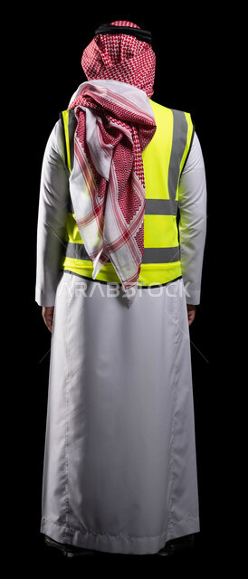 Supporting and developing the engineering sector, a portrait from the back of a Saudi Arabian Gulf engineer wearing a traditional uniform and a work protection jacket, supervising and following up on work, project management and auditing, engineering professions and jobs, full-length body photo, black background