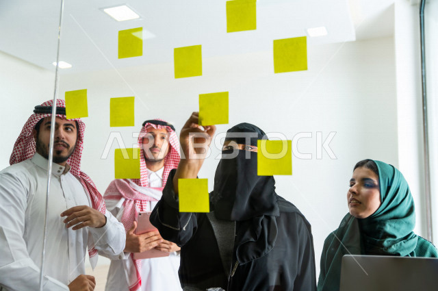 An administrative meeting with a group of Saudi and Gulf people, a meeting of businessmen and businesswomen together within the company, taking notes and tasks on paper, participating in setting goals, the work team, a Saudi company