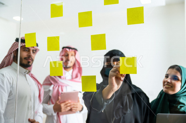 An administrative meeting with a group of Saudi and Gulf people, a meeting of businessmen and businesswomen together within the company, taking notes and tasks on paper, participating in setting goals, the work team, a Saudi company
