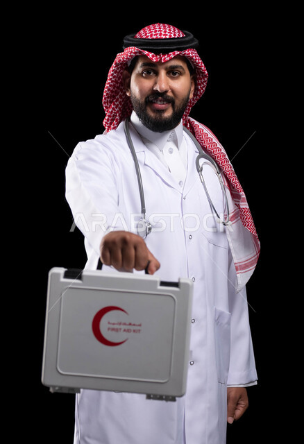 النظر إلى الكاميرا بإيماءات السرور ،الأدوات والمعدات الطبية اللازمة، مبادئ التعامل مع حالات الطوارئ، تقديم الخدمات الصحية الطارئة للمرضى، بورتريه لطبيب عربي سعودي خليجي يرتدي الثوب التقليدي و المعطف الطبي يحمل بيده حقيبة الاسعافات الأولية، خلفية سوداء