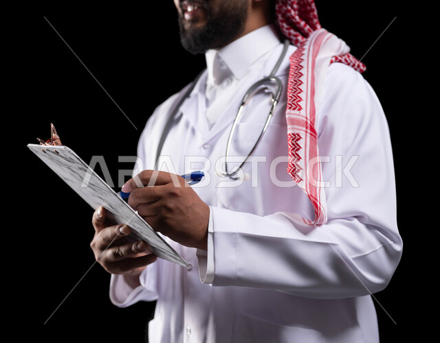 تدوين المعلومات العامة عن حالة المريض، بورتريه مقرب لطبيب عربي خليجي سعودي يرتدي الثوب التقليدي و المعطف الطبي ويحمل بيده ملفات المرضى، اعداد التقارير الطبية ، حسن التعامل مع المراجعين، العمل في القطاع الصحي، خلفية سوداء
