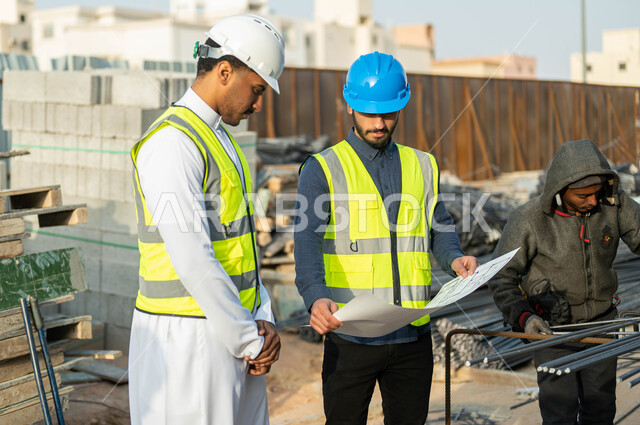 الإنشاءات والتصاميم الهندسيه في السعوديه, الاهتمام بالأساسيات الجيده للمبنى, مهندسان عربيان سعوديان خليجيان يرتديان الخوذه وستره الحمايه يقفان في موقع العمل, تبادل الأفكار حول إنجاز المشروع الهندسي, متابعه سير المخطط التنظيمي للمشاريع المعماريه