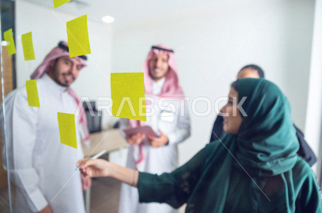 An administrative meeting with a group of Saudi and Gulf people, a meeting of businessmen and businesswomen together within the company, taking notes and tasks on paper, participating in setting goals, the work team, a Saudi company