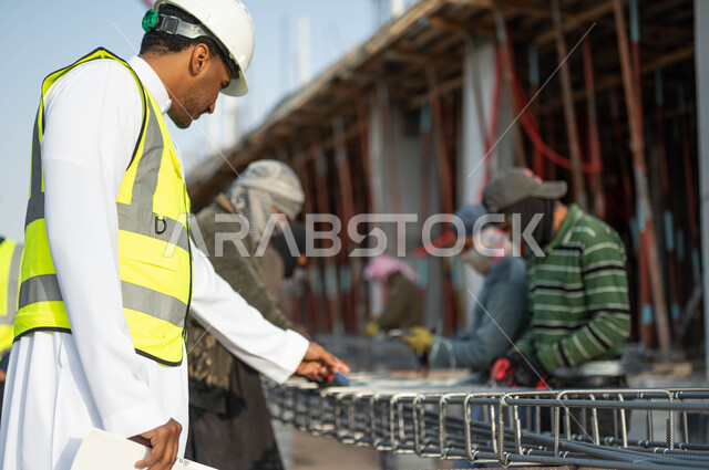 المهاره في اتقان العمل, التطور العمراني بسواعد أبناء الوطن, مهن ووظائف سعوديه, مجموعه من العمال يقومون بتجهيز وقص الحديد الصلب بمعدات وأدوات البناء, مهندس عربي خليجي سعودي يرتدي الستره وخوذه الحمايه يقوم بالإشراف ومتابعه سير االمشاريع المعماريه
