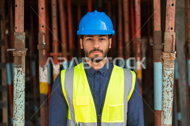 النمو والتطور العمراني على أيدي أبناء الوطن، الخطط و المشاريع الهندسيه المعمارية في موقع العمل ، صورة مقربة لمقاول عربي خليجي سعودي يقف باستقامة و يرتدي الخوذة وسترة الحماية ينظر إلى الكاميرا، العمل في القطاع الهندسي