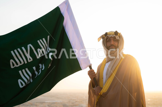 الحفاظ على الهوية الوطنية والفخر بتراثها ،ذكرى يوم التأسيس في 22 شباط، تاريخ توحيد البلاد في 1727 م، الزي الشعبي التقليدي في المنطقة الوسطى ، مؤسس الدولة السعودية الاولى الامام محمد بن سعود, سيد عربي خليجي سعودي يرتدي البشت والغترة يحمل بيده علم التأسيس 