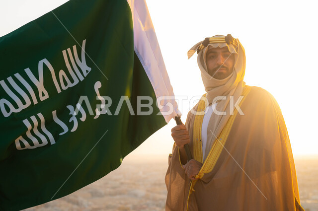 الحفاظ على الهوية الوطنية والفخر بتراثها ،ذكرى يوم التأسيس في 22 شباط، تاريخ توحيد البلاد في 1727 م، الزي الشعبي التقليدي في المنطقة الوسطى ، مؤسس الدولة السعودية الاولى الامام محمد بن سعود, سيد عربي خليجي سعودي يرتدي البشت والغترة يحمل بيده علم التأسيس 