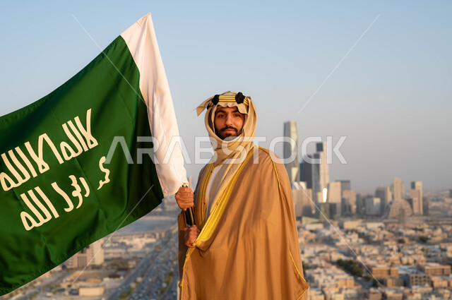  توحيد البلاد في 1727 م، نظرات الفخر و الاعتزاز بالانتماء للوطن، الزي الشعبي التقليدي في المنطقة الوسطى ، احياء ذكرى يوم التأسيس في 22 فبراير ، مؤسس الدولة السعودية الاولى الامام محمد بن سعود, رجل عربي خليجي سعودي يرتدي البشت والغترة يحمل بيده علم التأسيس