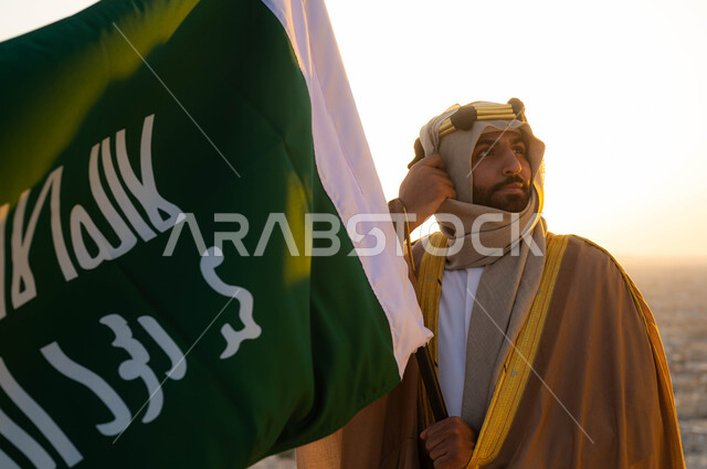 توحيد البلاد في 1727 م، نظرات الاعتزاز والفخر بالانتماء للوطن، مؤسس الدولة السعودية الاولى الامام محمد بن سعود, صورة مقربة لرجل عربي خليجي سعودي يرتدي البشت والغترة يحمل بيده علم التأسيس, الزي الشعبي في المنطقة الوسطى, الإحتفال بذكرى يوم التأسيس في 22 فبراير