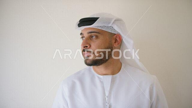  الإهتمام بالمظهر الخارجي، صورة مقربة لرجل عربي إماراتي خليجي يرتدي الكندورة و الغترة الإماراتية وينظر إلى شيء ما، ايماءات التفكير والتأمل و شرود الذهن والتخطيط للمستقبل، خلفية بيضاء