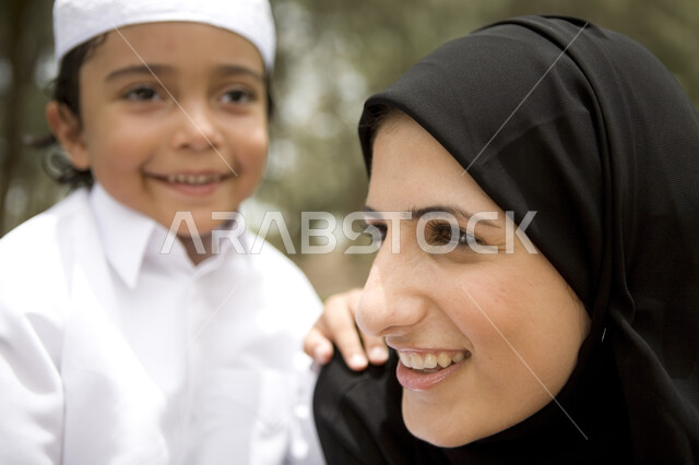 عطلة نهاية الاسبوع, اللعب مع الابناء, ايماءات تدل على السعادة, رحله عائليه في يوم مشمس, صورة مقربة لطفل عربي إماراتي خليجي يلعب مع والدته في المنتزه, مفهوم الأسره السعيدة، قضاء أوقات عائلية ممتعة