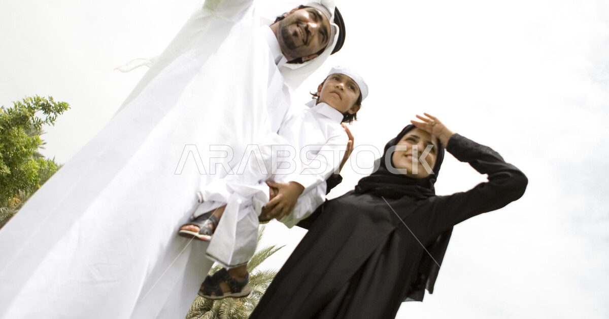 أم واب يحملون ابنهم في احدى الحدائق العامة, ايماءات النظر والاشارة الى ...