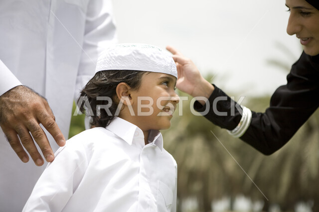 ايماءات الحب والعطف على الابناء, قضاء وقت ممتع في الحديقه , صورة مقربة لعائله عربيه إماراتية خليجيه مكونه من ثلاث أفراد, قضاء يوم العطلة في الحديقة, إجازه صيفيه ممتعة, الاستمتاع باللعب الجماعي في المنتزه, تسليه وترفيه, خلفية الطبيعة الخضراء