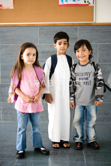 النظر إلى الكاميرا بإيماءات السعادة بالعودة إلى المدرسة, الاستعداد للعام الدراسي الجديد, تلاميذ عرب خليجيون إماراتيون يرتدون حقيبة الظهر المدرسية, المدارس الأكاديمية في الإمارات العربية المتحدة, صورة الجسم بالطول الكامل